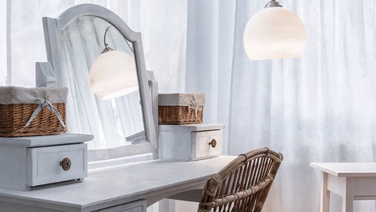 Shabby chic white dressing table with mirror, wicker chair, and storage baskets, highlighting the real benefits of owning a vanity for makeup and jewelry organization.