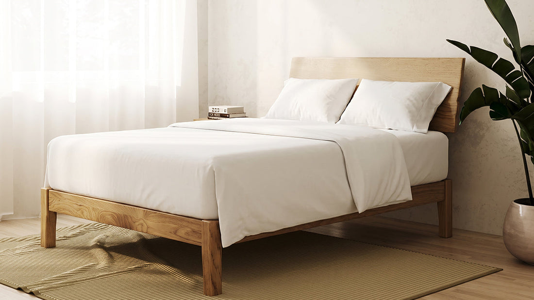 Timber bed frame with white bedding in bright neutral bedroom