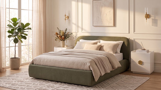 Green upholstered bed with layered neutral bedding in bright bedroom