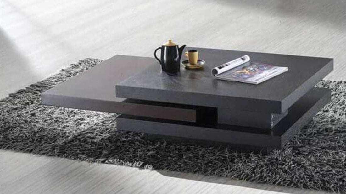 Modern dark gray geometric coffee table on a shag rug with a black teapot and magazine, reflecting contemporary personality in furniture.