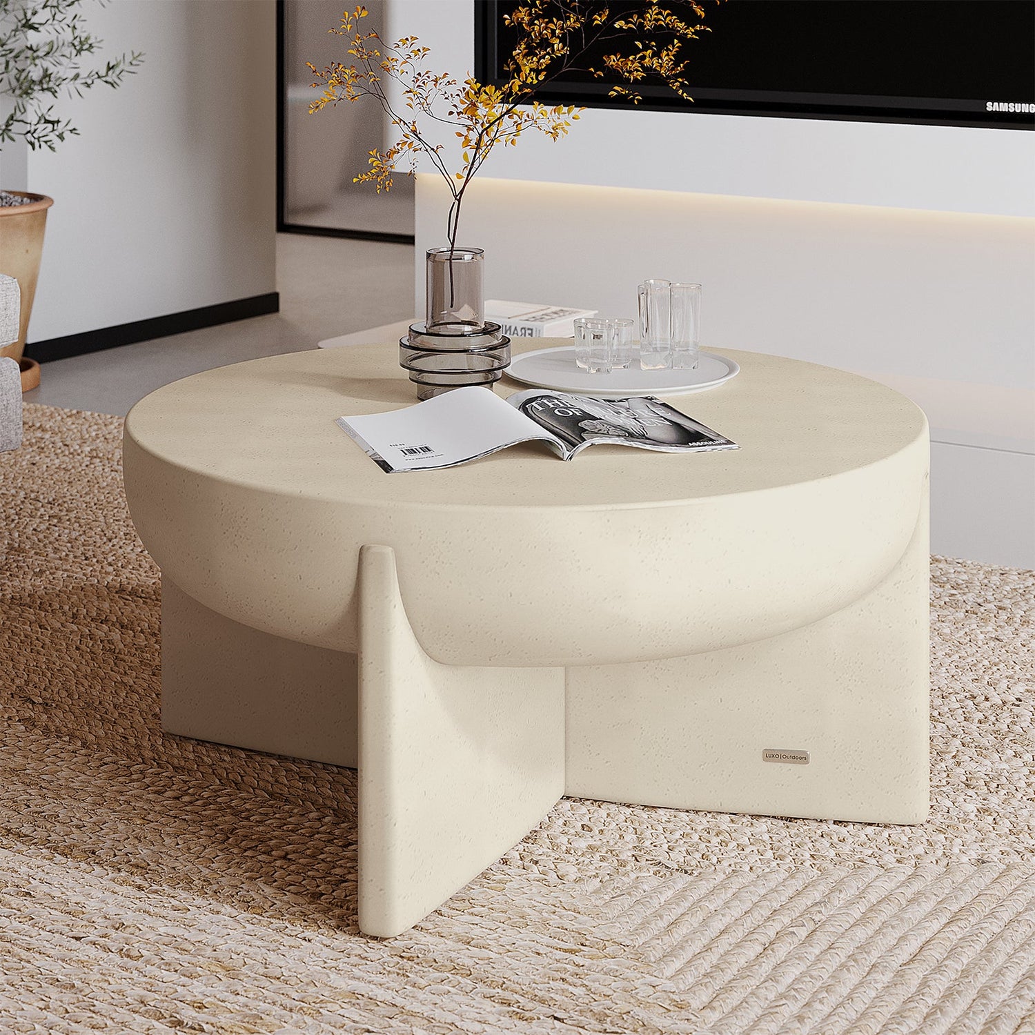 Off-white sculptural round coffee table with a matte stone finish and intersecting pedestal base.