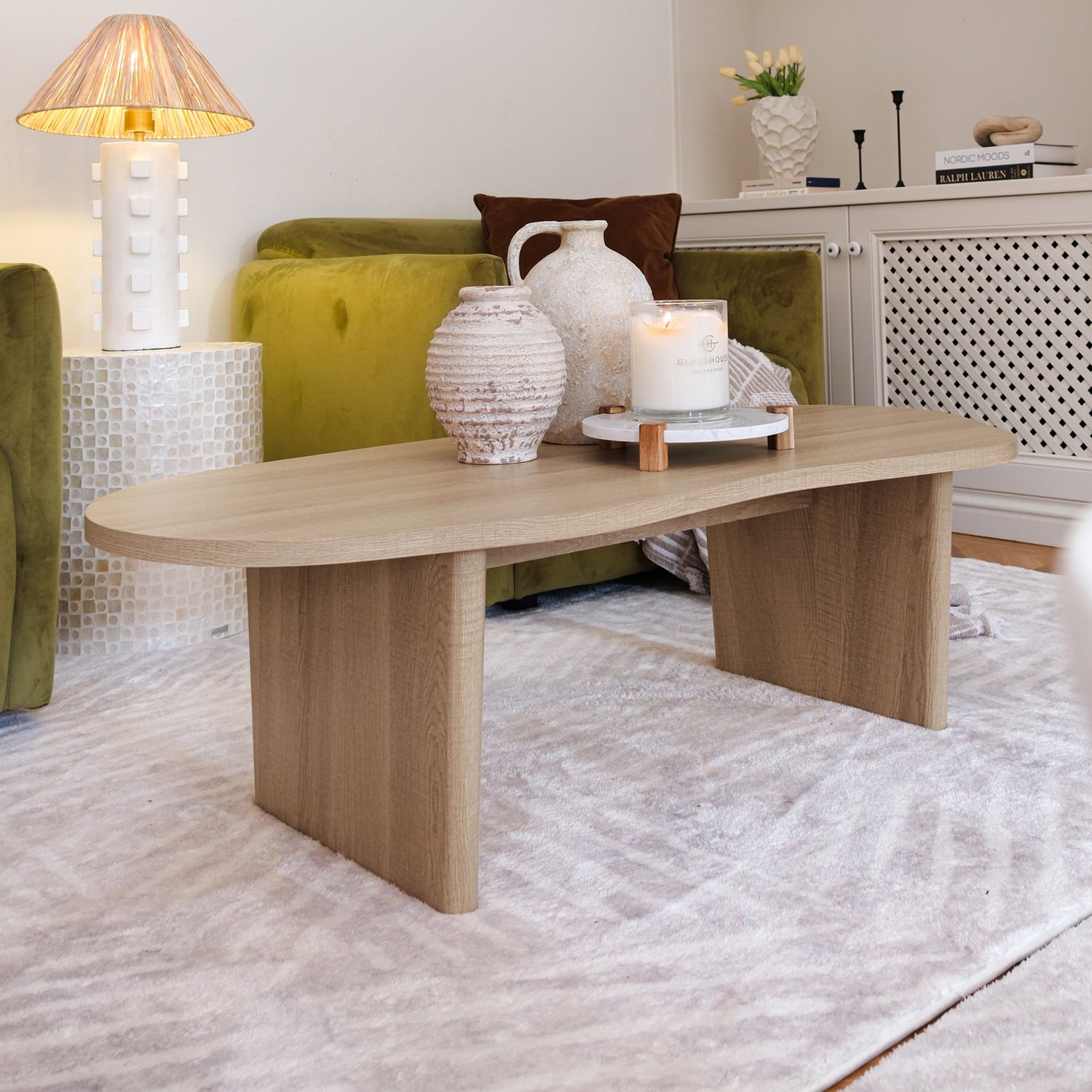 Oak coffee table with cross-base design in living room setting with yellow sofa and white decor accessories