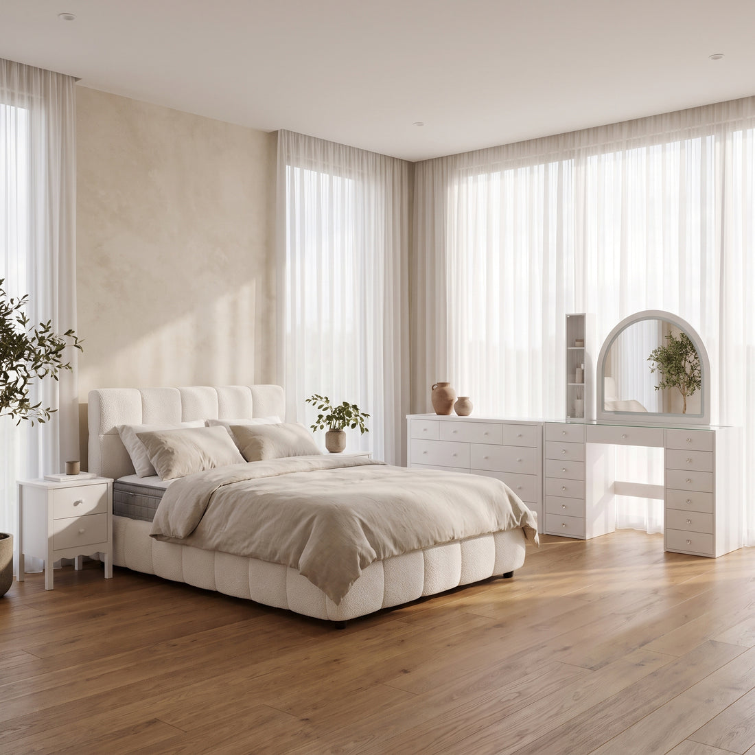 Modern neutral-toned Airbnb bedroom featuring a cream boucle upholstered bed dressed in beige linens, a matching white nightstand, and a coordinated dresser and arched vanity setup against floor-to-ceiling sheer curtains.