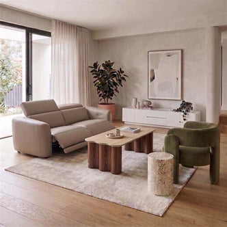 Beige leather recliner sofa paired with a wavy wood coffee table, an olive green velvet armchair, and a white TV unit in a modern living room