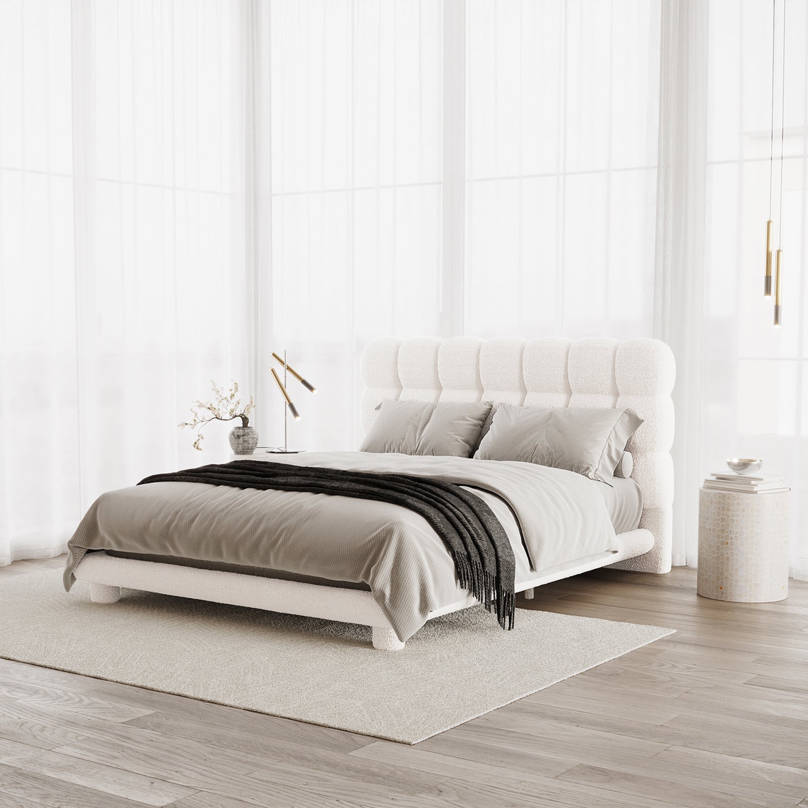 Aina Queen Boucle Bed Frame in Cream White features a plush tufted headboard, dressed in neutral linens with a charcoal throw. Side tables with decor flank the bed, creating a serene, airy bedroom setting.