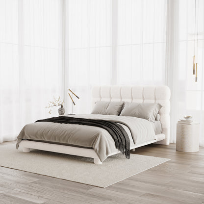 Aina Queen Boucle Bed Frame in Cream White features a plush tufted headboard, dressed in neutral linens with a charcoal throw. Side tables with decor flank the bed, creating a serene, airy bedroom setting.