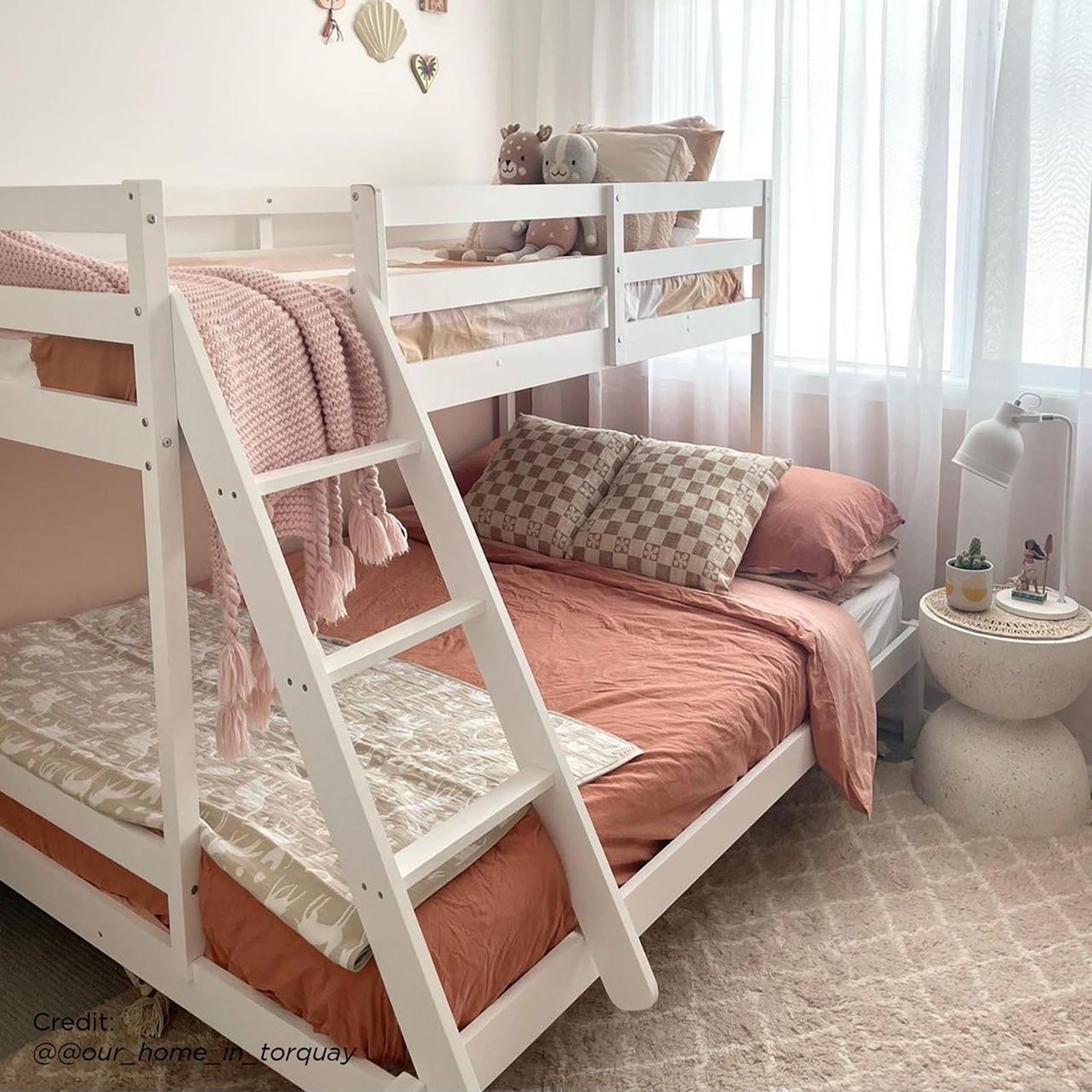 Antonia Solid Wood Triple Bunk Bed - White shown in a stylish room, featuring a double bottom bunk and single top bunk with guard rails and a reversible ladder, highlighting space-saving design.