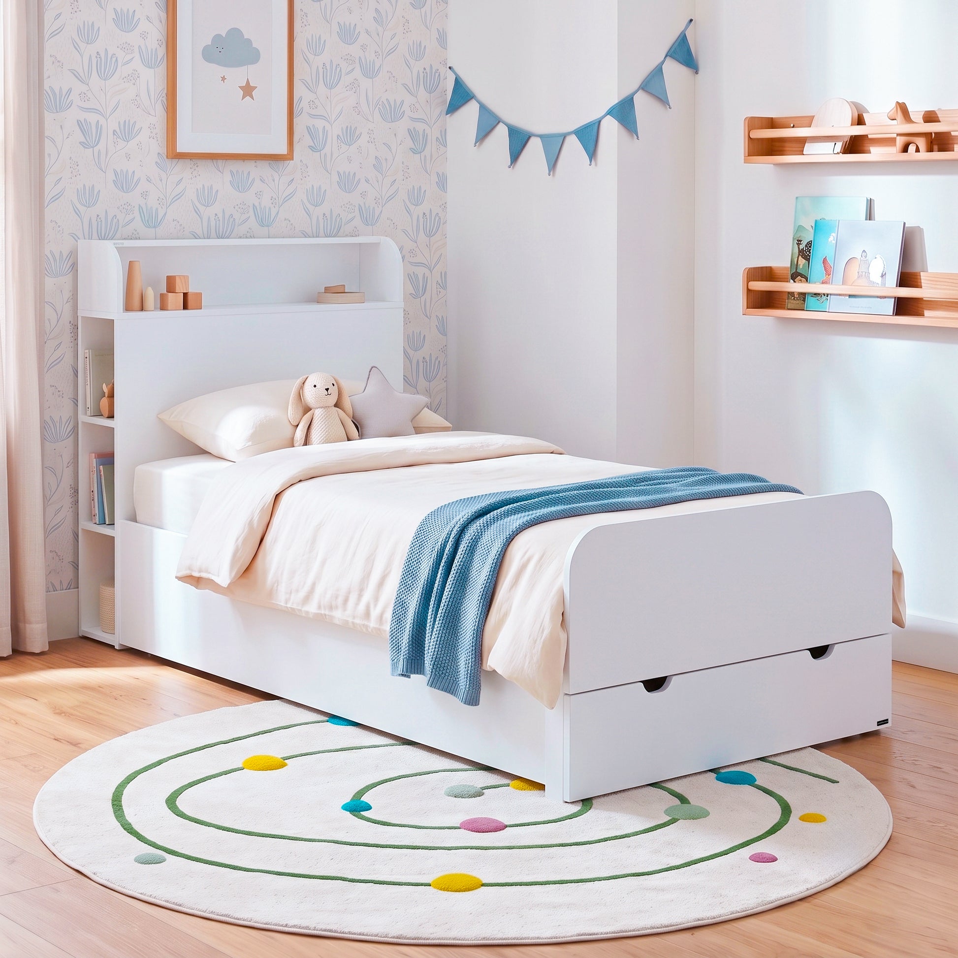 White children's bed with shelf headboard and pull-out drawer in a decorated bedroom.