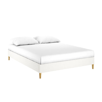 Celina Queen Boucle Fabric Bed Base in Cream White, featuring a minimalist design with white upholstery, a white mattress, two pillows, and short, tapered wooden legs for a sleek, modern look.
