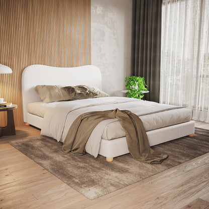 Ginnie Bouclé Curved Queen Bed Frame - Cream White showcased in a contemporary bedroom with a curved headboard, neutral bedding, light wood slat accent wall, and a plush brown area rug.