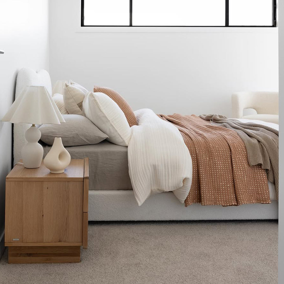 Ginnie Queen Curved Bouclé Cloud Bed Frame in Cream White, featuring a plush curved headboard and elegant bouclé fabric, set in a minimalist bedroom with neutral linens and a light taupe carpet.