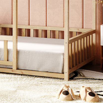 Jesse Kids Single Solid Pine Wood House Bed Frame in White, featuring a wooden slatted design and light-gray fitted sheet, set against a soft pink wall with a plush cream rug and dog-face slippers.