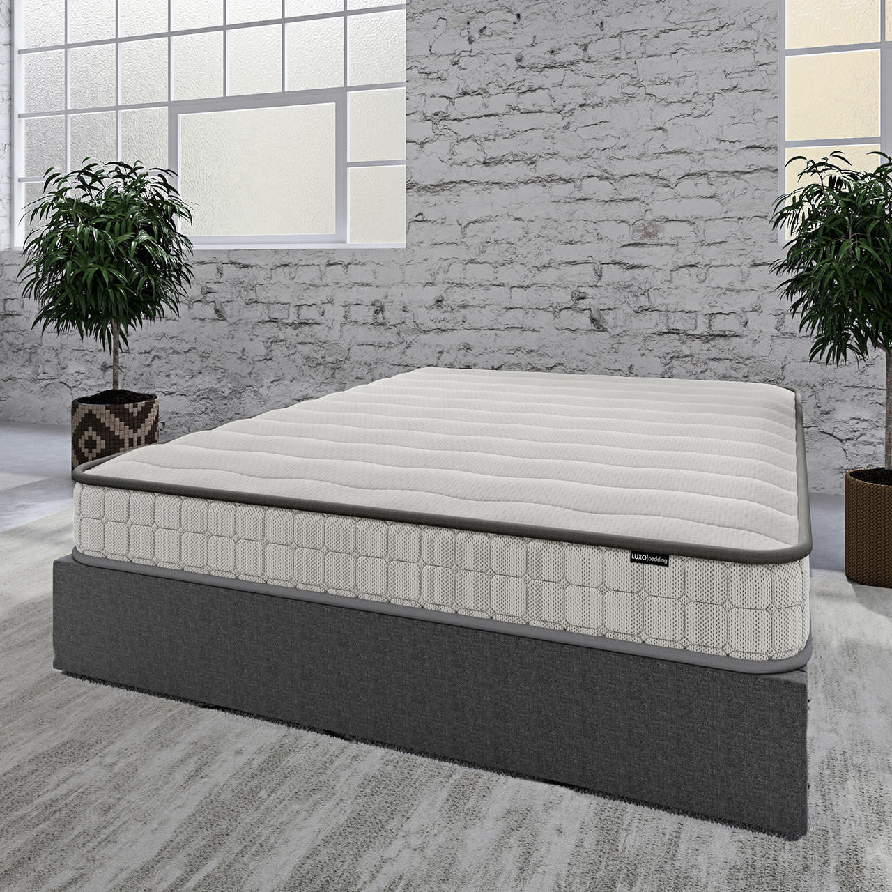 Logan & Cybele Queen Murphy Bed & Mattress Set in White features a sleek light-grey mattress on a dark-grey base, set in a minimalist room with potted plants and a whitewashed brick wall.