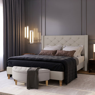 Maggie Queen Winged Fabric Bed Frame in Warm Grey, featuring a tufted headboard and matching bench, set in a stylish bedroom with accent pillows, a black blanket, and pendant lights.