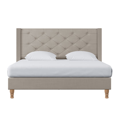 Maggie Queen Winged Fabric Bed Frame in Warm Grey features a button-tufted upholstered headboard, white bedding, and wooden legs, exuding elegance and stability with a Chesterfield-style design.