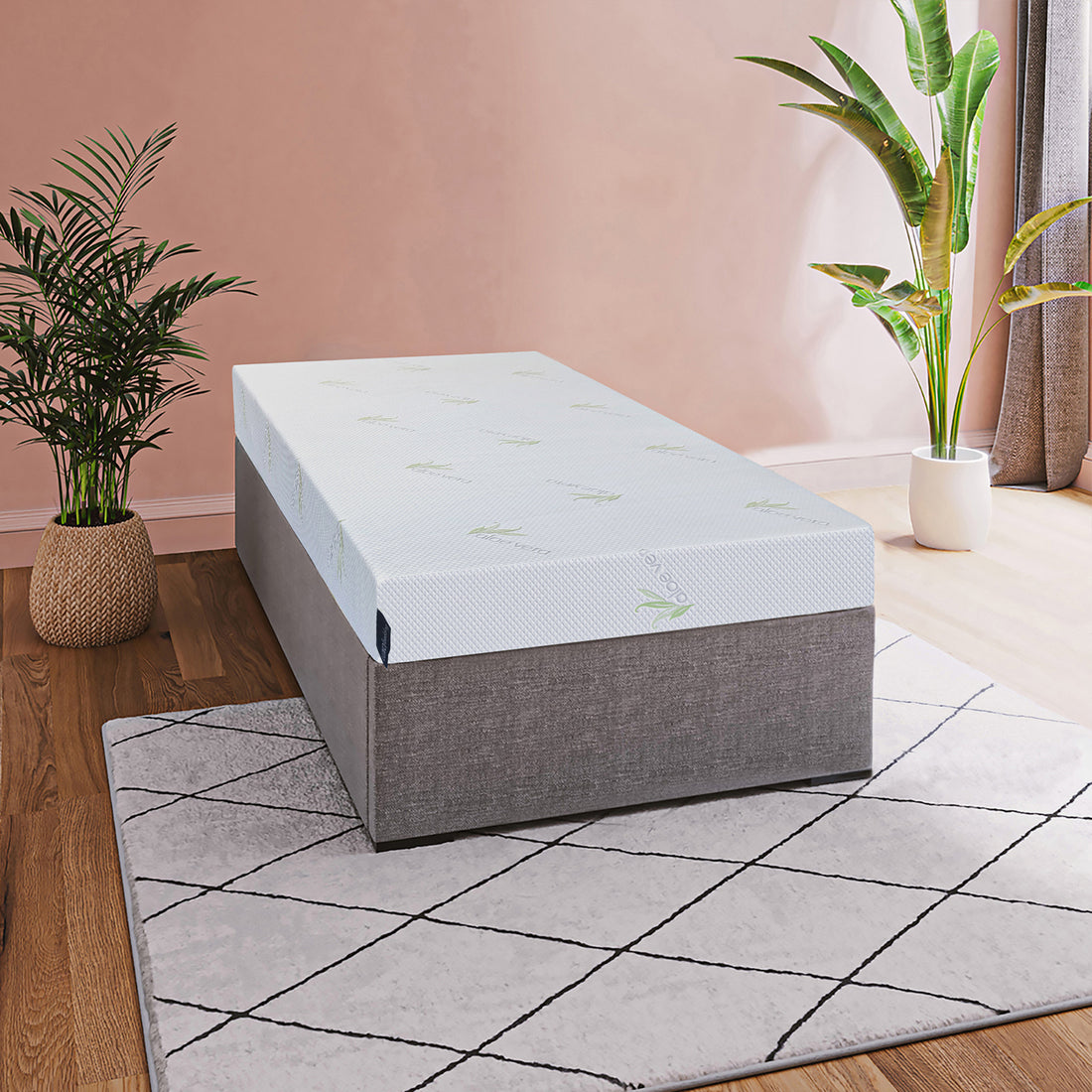 Calypso 20cm Cool Gel Memory Foam Single Mattress topper with subtle green leaf pattern on a gray platform, set in a stylish room with wood flooring and potted plants.