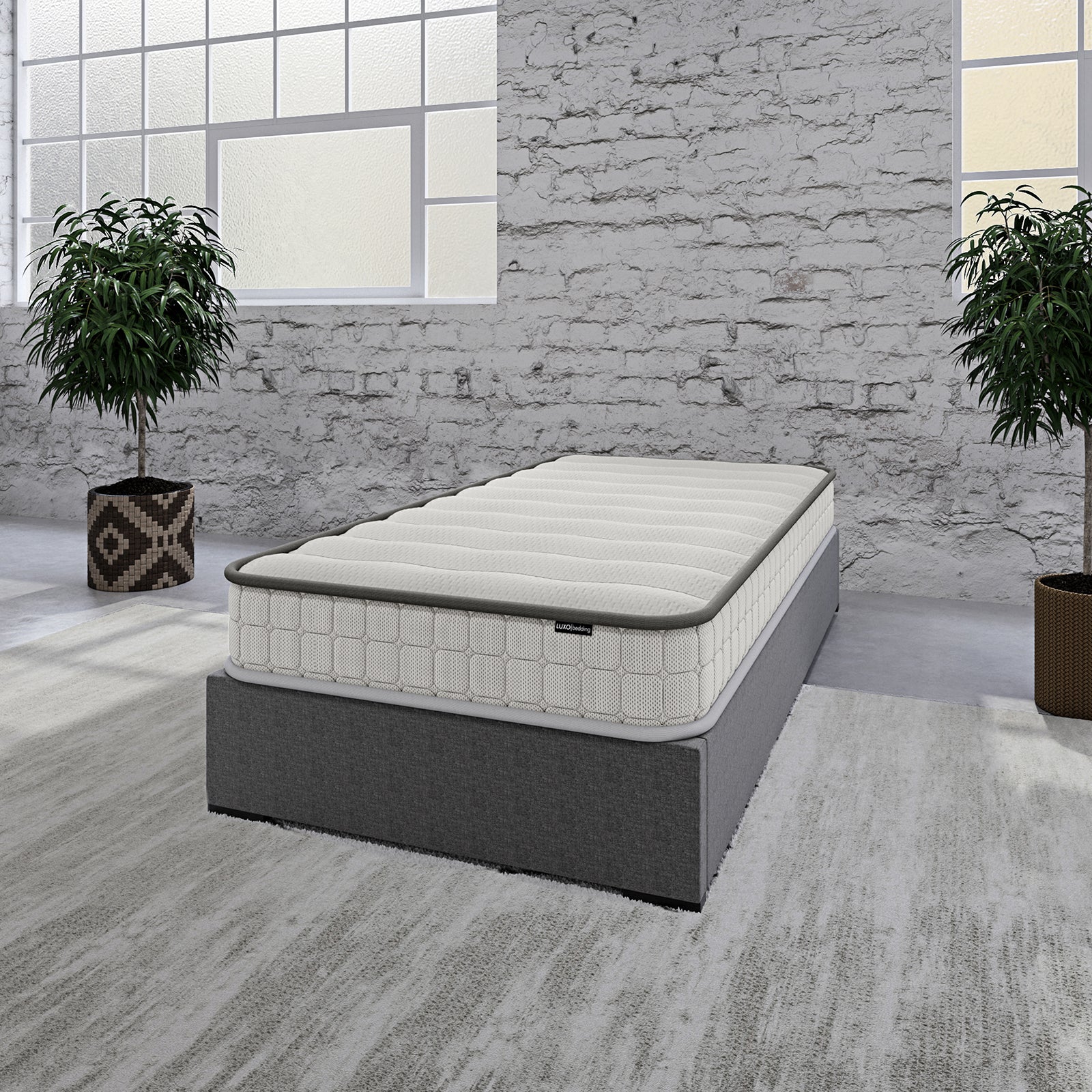Cybele Single 20cm Pocket Spring Memory Foam Mattress on a dark grey platform with quilted top, highlighted in a minimalist industrial-style setting with potted plants and concrete flooring.