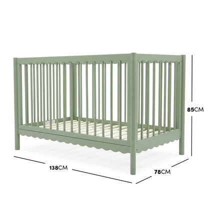 Sage green timber baby cot with scalloped base molding and dimensions diagram.