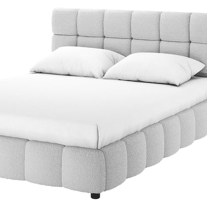 King Bouclé Fabric Bed Frame in Light Grey with a plush, grid-style headboard and tufted base, featuring a simple white sheet and pillows, viewed from a low, front-side angle.