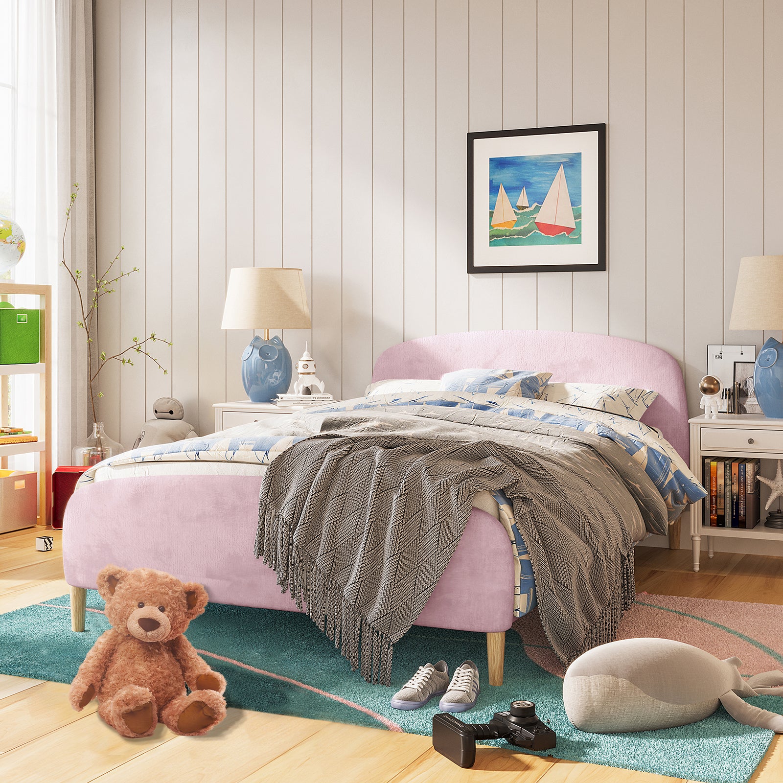 Theron Double Upholstered Velvet Bed in Light Pink, featuring a plush pink frame with a curved headboard, styled with blue-and-white bedding, gray throw, and surrounded by colorful and playful room accents.
