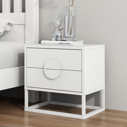 Abigail 55cm 2-Drawer Bedside Table w/ Handle - White beside a bed, featuring arc handles, atop a metal base, with a book, geometric bear figurine, and vase on its surface.
