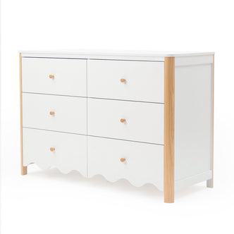 White six-drawer dresser with scalloped bottom edge and wood accents on white background