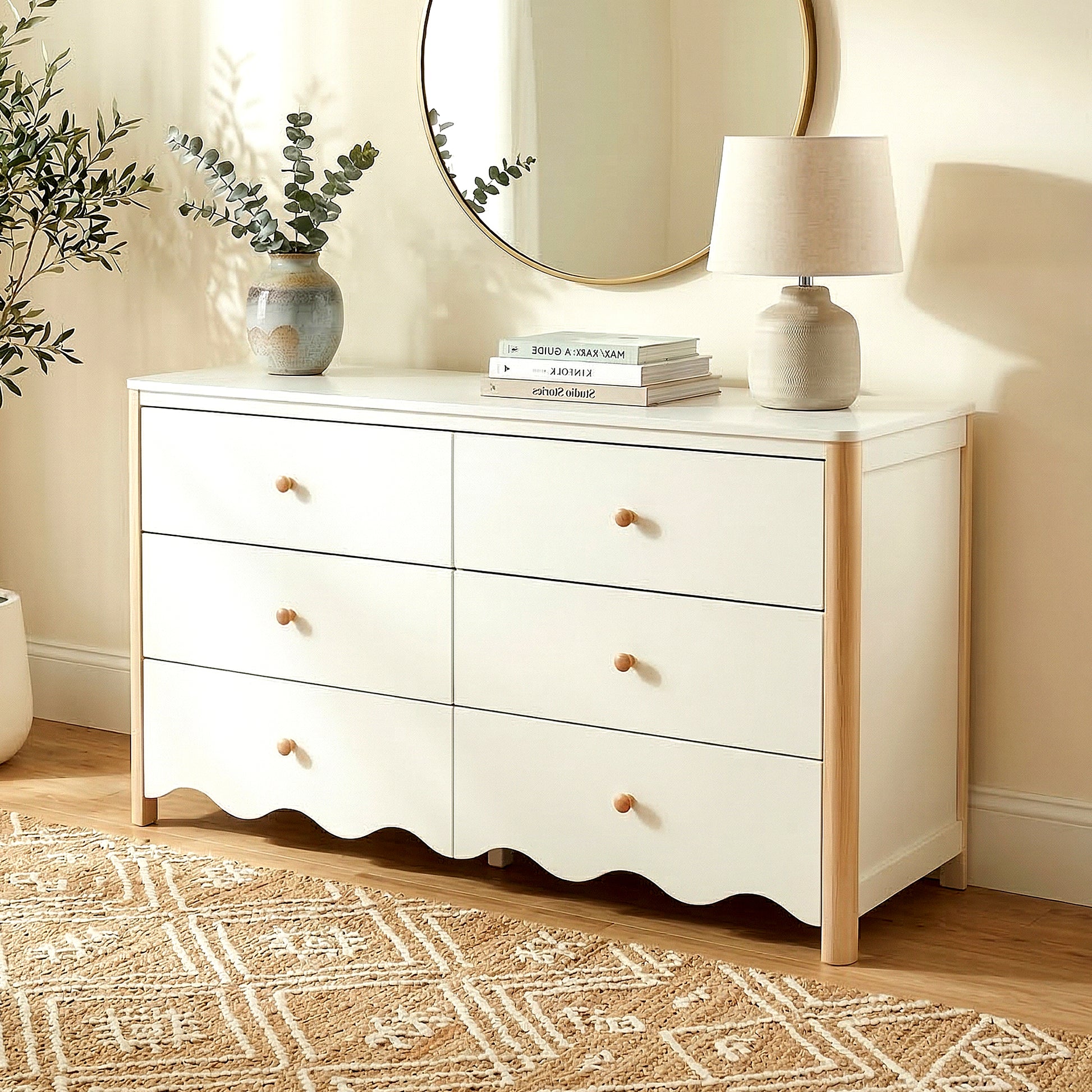 White six-drawer dresser with wood handles in a styled room with rug, lamp, and mirror