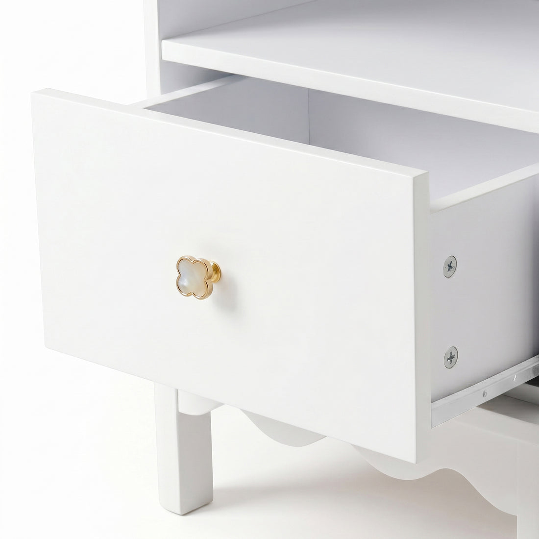 Detail of gold knob and partially opened drawer on white background