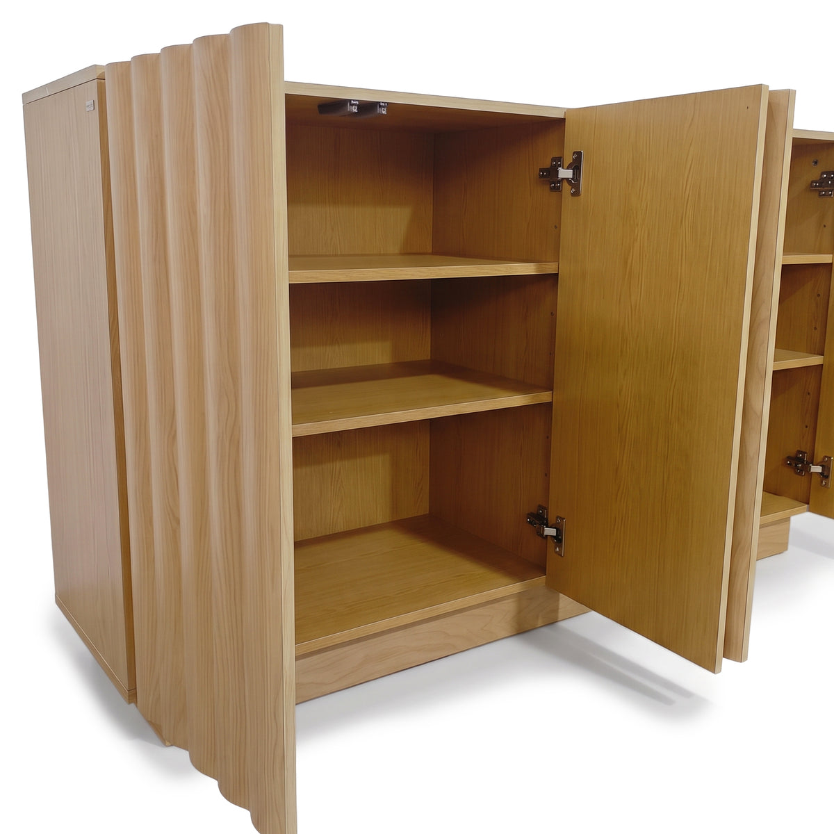 Oak sideboard with open fluted doors revealing interior shelves and concealed hinges against a plain white studio background.
