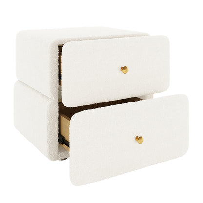 Tyla Boucle Bedside Table in Cream White, cube-shaped, upholstered in boucle fabric with two drawers featuring brass knobs; one drawer is partly open, highlighting its elegant, functional design.