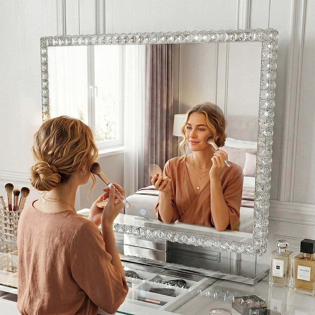 Young woman using a blush brush, seated at a vanity table featuring the Sylor 100cm LED Crystal Diamond Vanity Mirror in White, showcasing its crystal edges and expansive reflective surface.