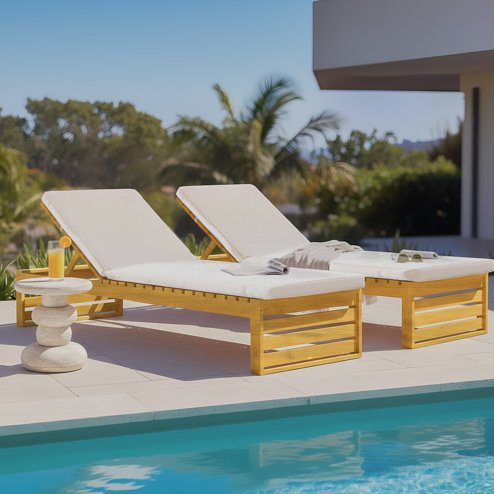 Pair of timber outdoor sun loungers with adjustable backrests and cream cushions, situated poolside on a stone patio.