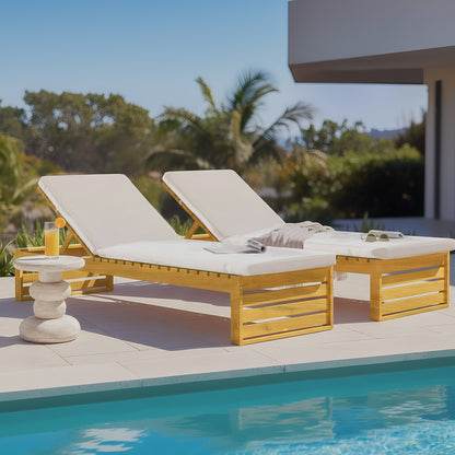 Pair of timber outdoor sun loungers with adjustable backrests and cream cushions, situated poolside on a stone patio.