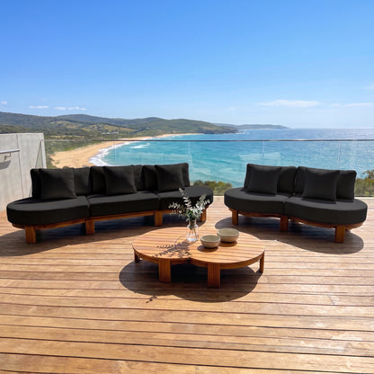 Outdoor patio sectional sofa set with coffee table on a wooden deck overlooking the ocean