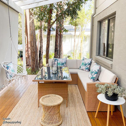 Ballena 6 Seater Wicker Outdoor Dining Sofa Set, featuring a wicker sofa with padded cushions and a matching dining table with a clear tempered glass top, adorned with a houseplant on the table.