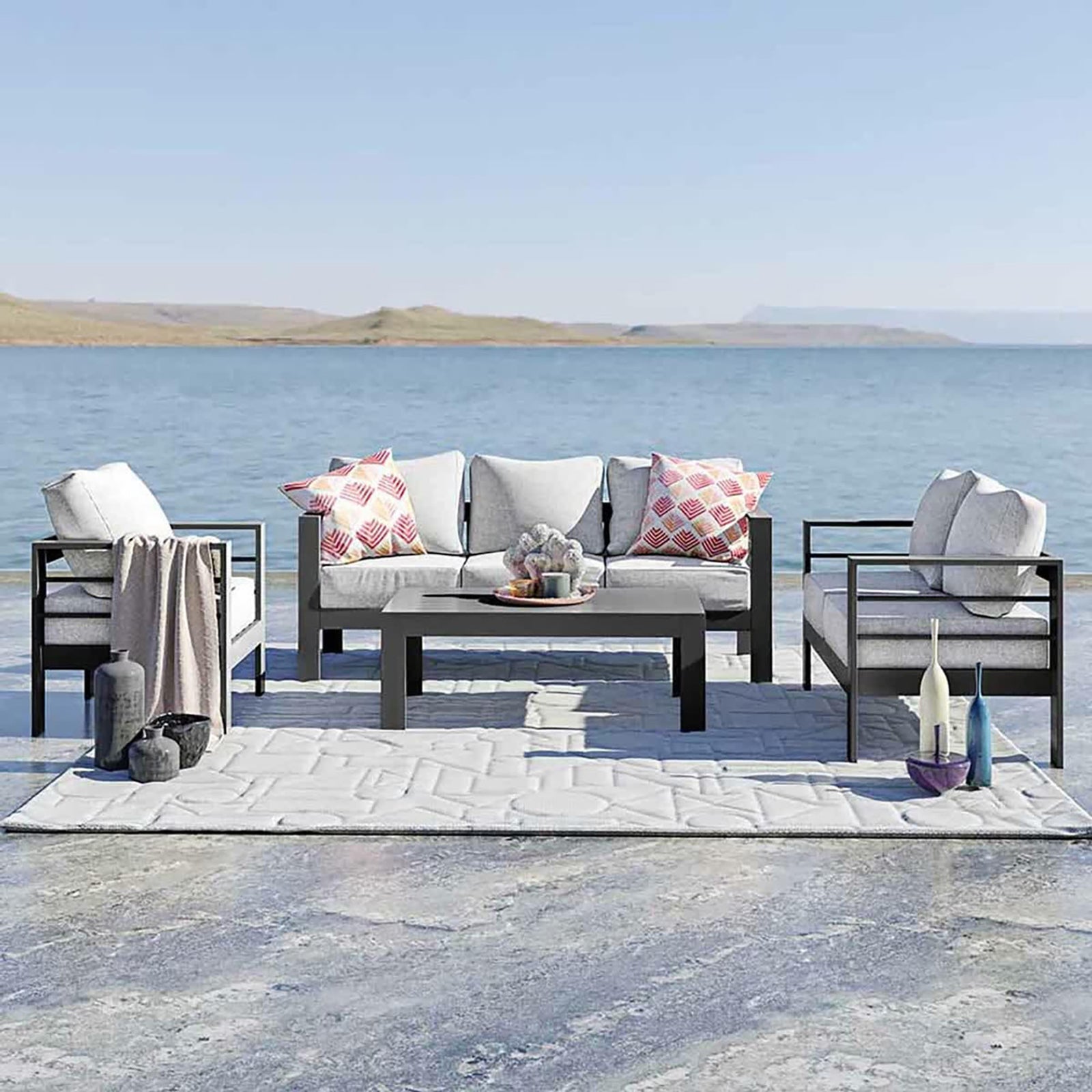 Luxo Bayo 6 Seater Aluminium Outdoor Furniture Set – Grey, featuring plush cushions on a sleek, powder-coated aluminium frame, visible on a chair, perfect for outdoor lounging by the water.