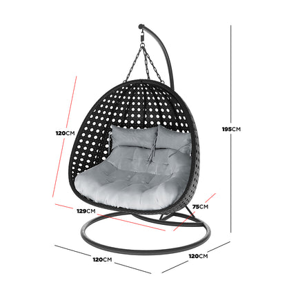 Buena 2 Person Wicker Outdoor Hanging Egg Chair in Black features a rattan-style shell, plush cushions, and a sturdy metal stand, offering spacious double seating for outdoor relaxation.