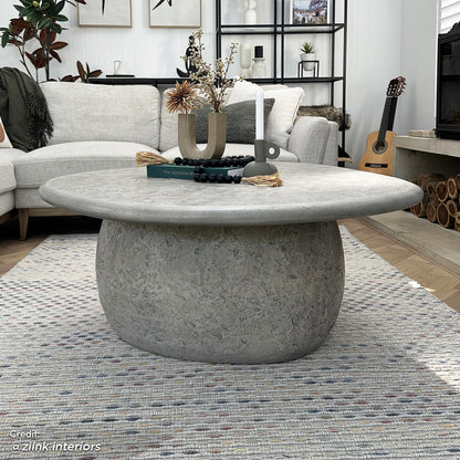 Cam Indoor & Outdoor Round Concrete Coffee Table – Stone, featuring a sturdy, organic round design with a natural concrete texture, ideal for modern farmhouse aesthetics, shown in a cozy living room setting.