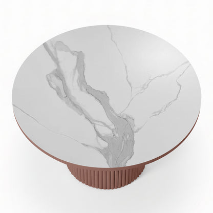 Top-down view of a round white stone dining table with grey marble-effect veining and a terracotta-colored fluted pedestal base.