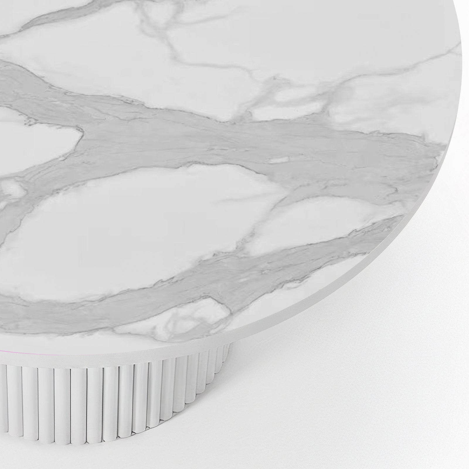 Close-up of a round dining table featuring a white stone top with grey marble veining and a white fluted pedestal base.