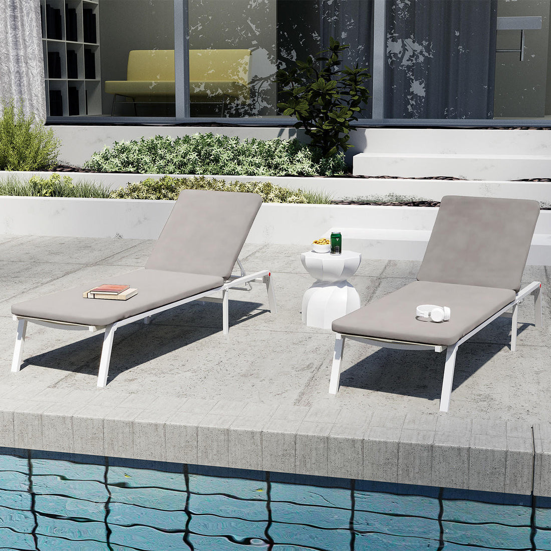 Jabari Outdoor Sun Loungers with Cushions Set of 2 in Warm Grey, featuring slim white metal frames and smooth cushions, with a small white side table in between, poolside setting.