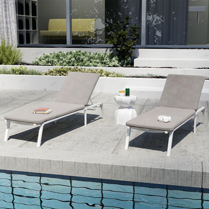 Jabari Outdoor Sun Loungers with Cushions Set of 2 in Warm Grey, featuring slim white metal frames and smooth cushions, with a small white side table in between, poolside setting.