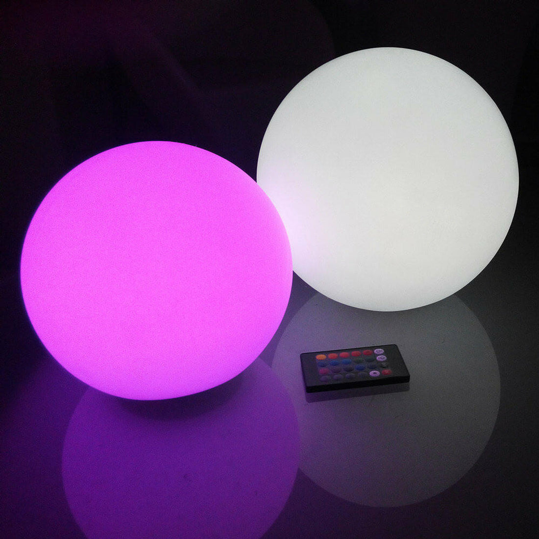 Close-up of the Waterproof Outdoor LED Ball Lights Décor 50cm, featuring two glowing LED balls alongside a remote control, highlighting the product's sleek, round design and wireless functionality.