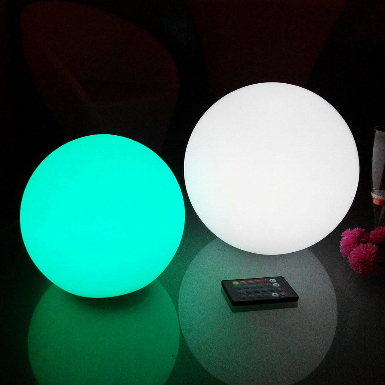 Close-up of two glowing Luxo Outdoor LED Ball lights, showcasing their sleek round design with a remote control, highlighting the Waterproof Outdoor LED Ball Lights Décor 50cm's floatable feature for magical outdoor settings.