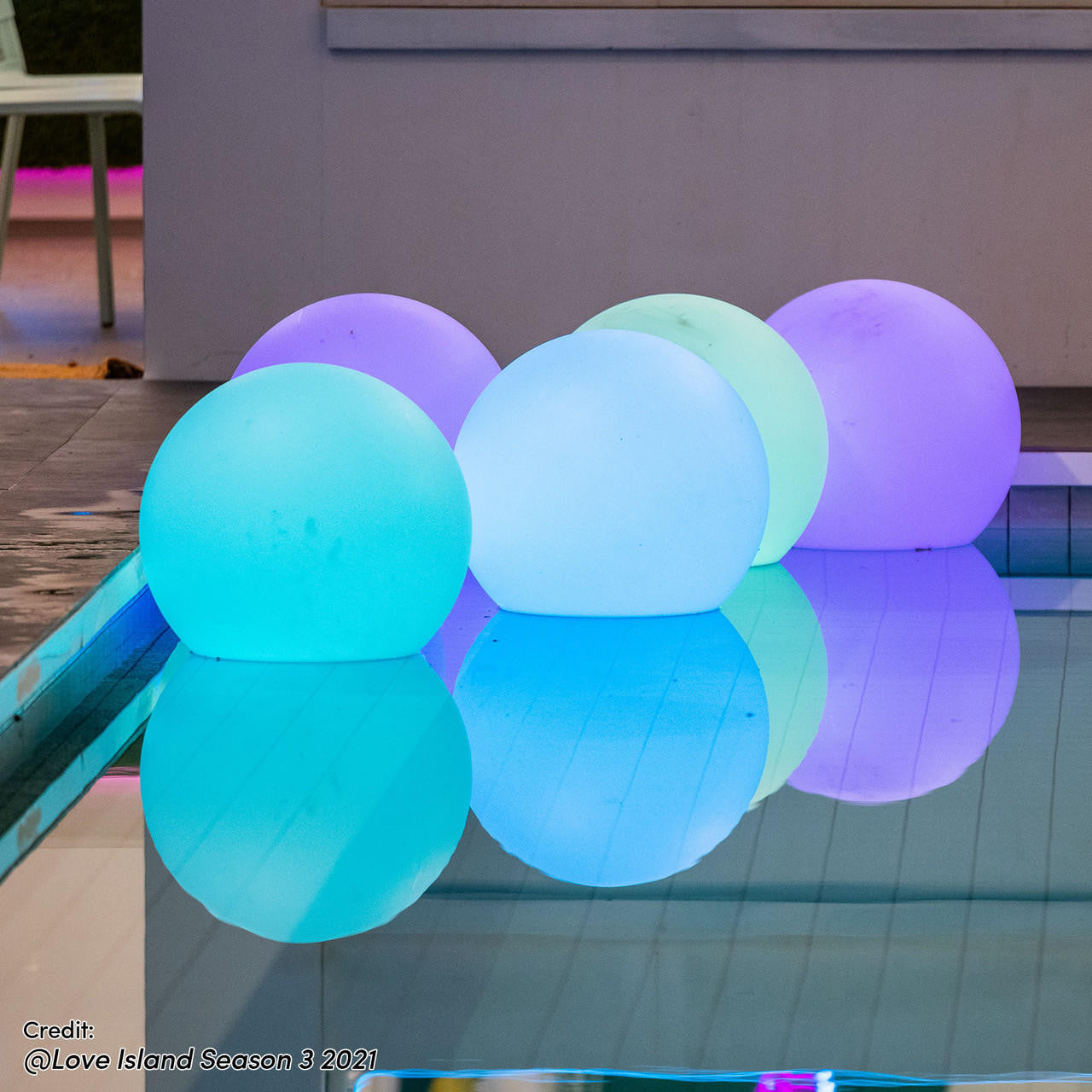 Sphero Floating LED Ball Bundles — Outdoor 60 & 40 cm, five softly glowing spheres by a pool, reflecting pastel hues on water, enhancing outdoor ambiance with a sophisticated, waterproof design.
