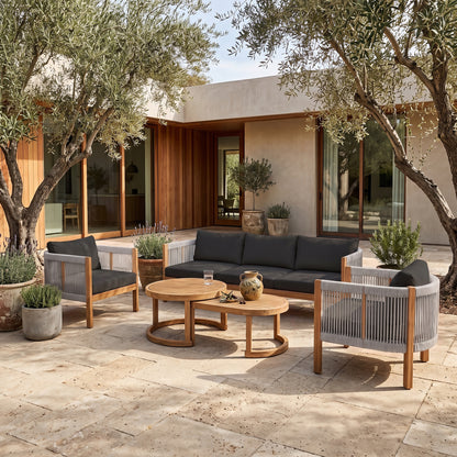 Outdoor patio furniture set arranged on a stone patio with plants and a house in the background