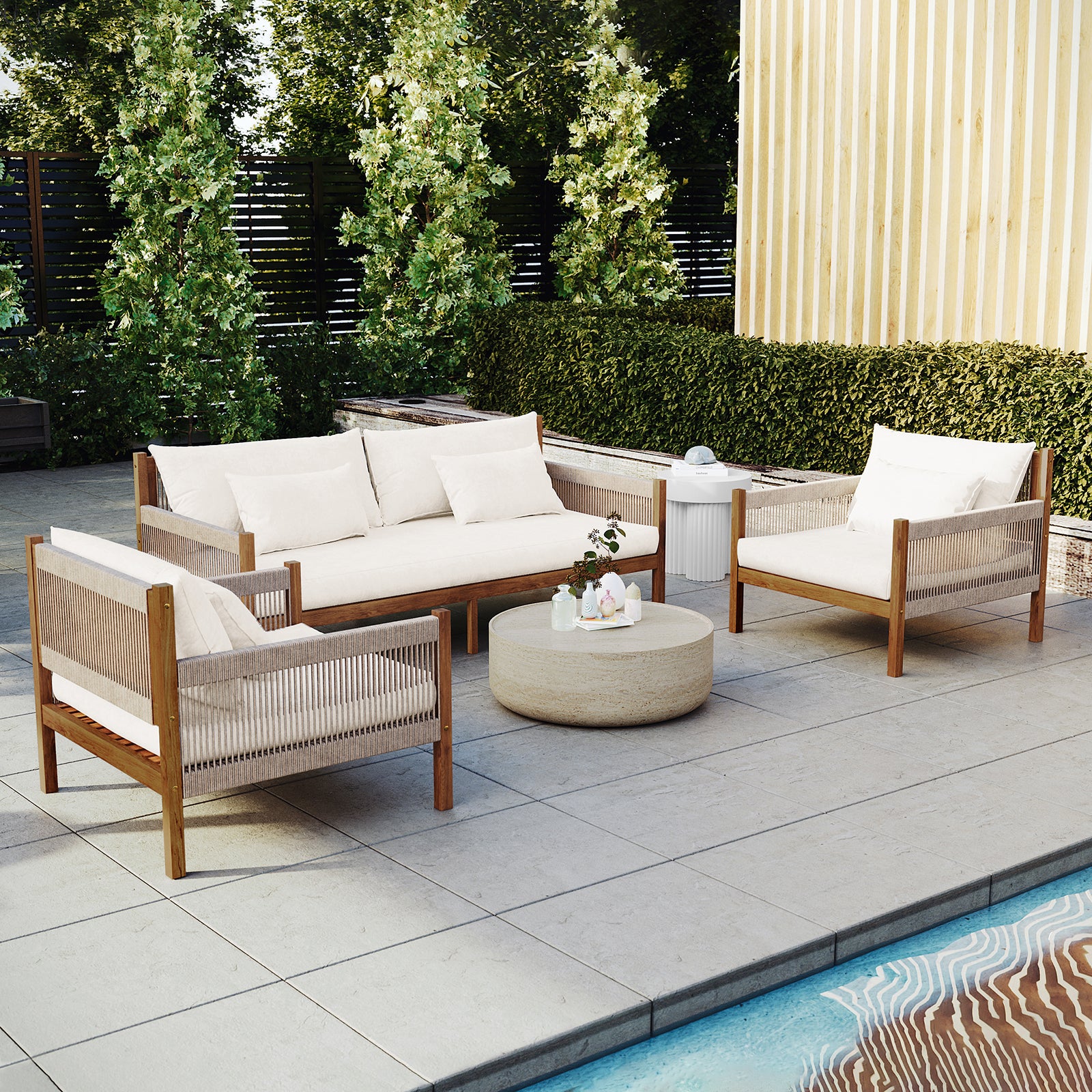 Savin & Myrtle Outdoor Sofa Set with Coffee Table in Beige features a two-seater sofa, two armchairs with woven sides, and a stone coffee table, all set by a pool.