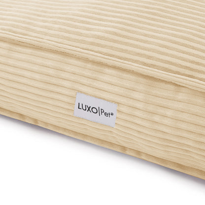 Dax Extra Large Corduroy Dog Bed – Beige Comfort features a close-up of a beige, textured corduroy pillow with a visible label, showcasing its plush fibre fill and durable design.