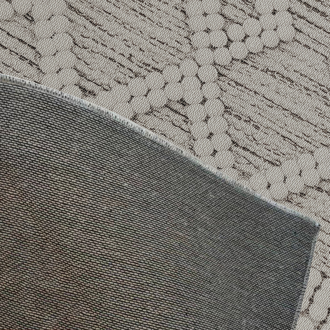 Benita Modern Abstract Tufted Rug 120x180cm featuring a plush, contemporary design with intricate floral patterns, displayed over a solid charcoal-gray textile with stitched edges for contrast.