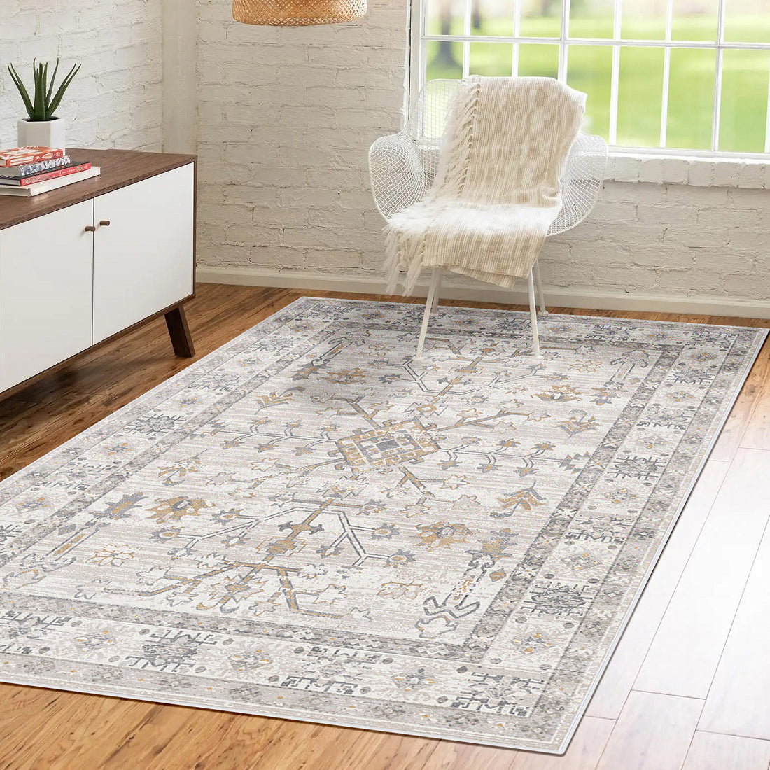 Bortan Persian Indoor Rug 160x230cm on hardwood floor, featuring muted neutrals with a distressed medallion pattern, enhancing a minimalist living space with a mid-century sideboard and white mesh chair.